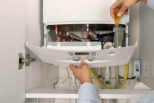 HVAC technician repairing an indoor boiler in Provo
